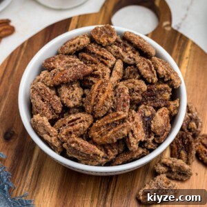 Cinnamon Sugar Candied Pecans Recipe for Snacking & Gifts 11 Sugar coated pecans in a white bowl with a small jar of sugar behind the bowl.