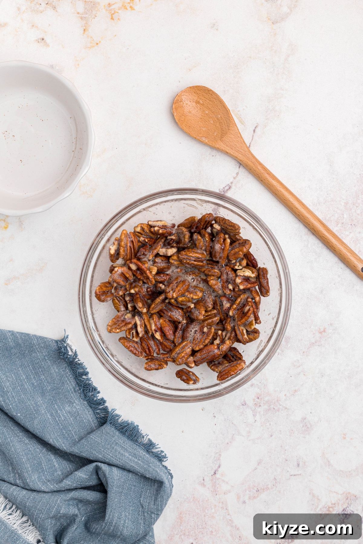 Cinnamon Sugar Candied Pecans Recipe for Snacking & Gifts 5 Pecans tossed together with whisked egg white in clear glass bowl.