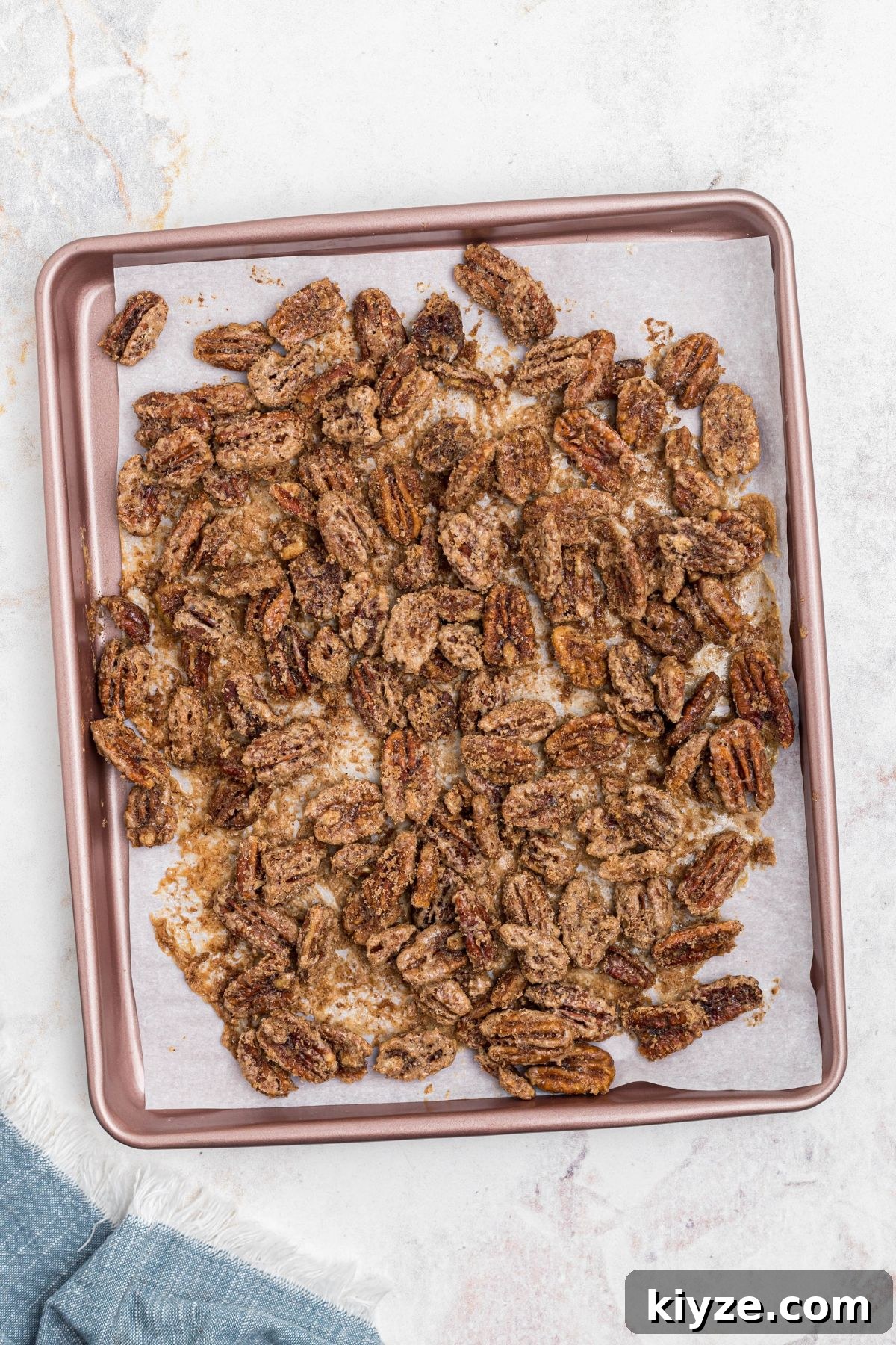 Cinnamon Sugar Candied Pecans Recipe for Snacking & Gifts 9 Pecans on baking sheet lined with parchment paper, coated with sugar, after baking.