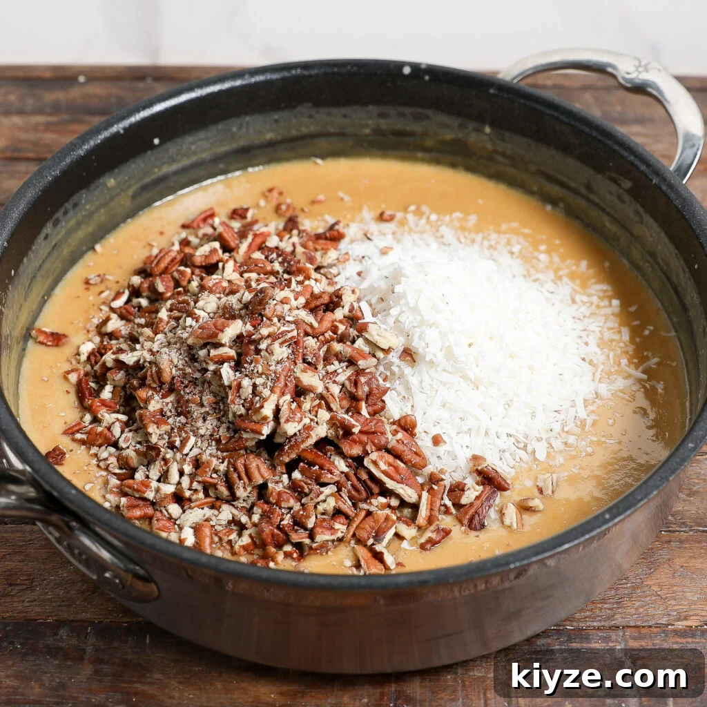 German Chocolate Cake Frosting Recipe: Rich Coconut-Pecan Icing 5 A saucepan on a wooden surface contains a light brown batter topped with chopped pecans and shredded coconut, ready to be mixed for classic German Chocolate Cake Frosting.