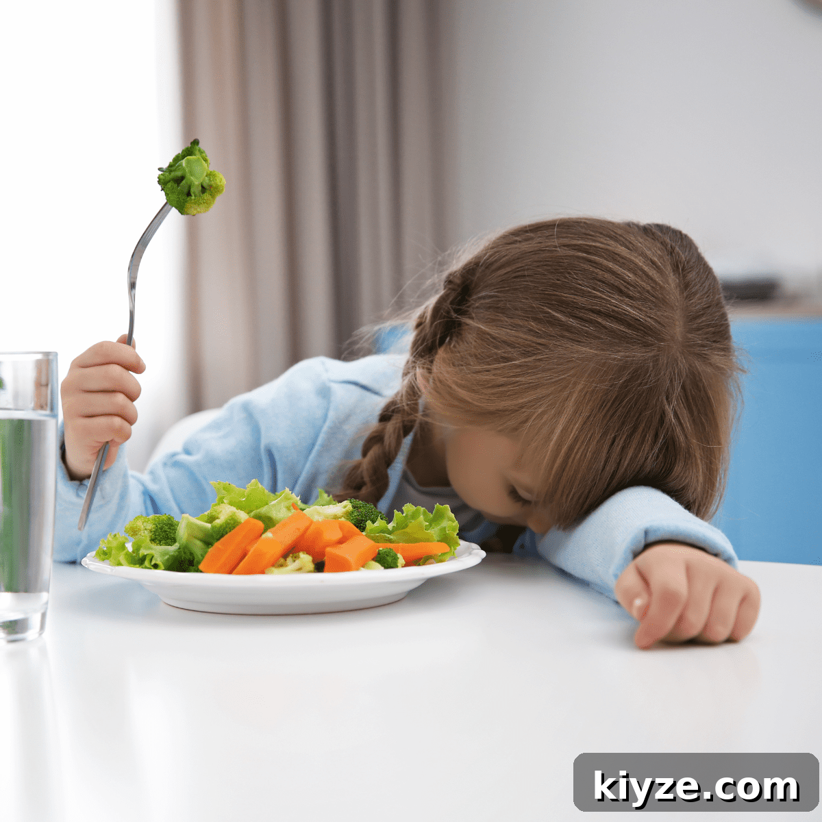 Prevent Toddler Grazing: Simple Strategies to Curb Constant Snacking 3 Young girl with head down on table, next to a plate of vegetables, holding a fork in the air with a piece of broccoli on it