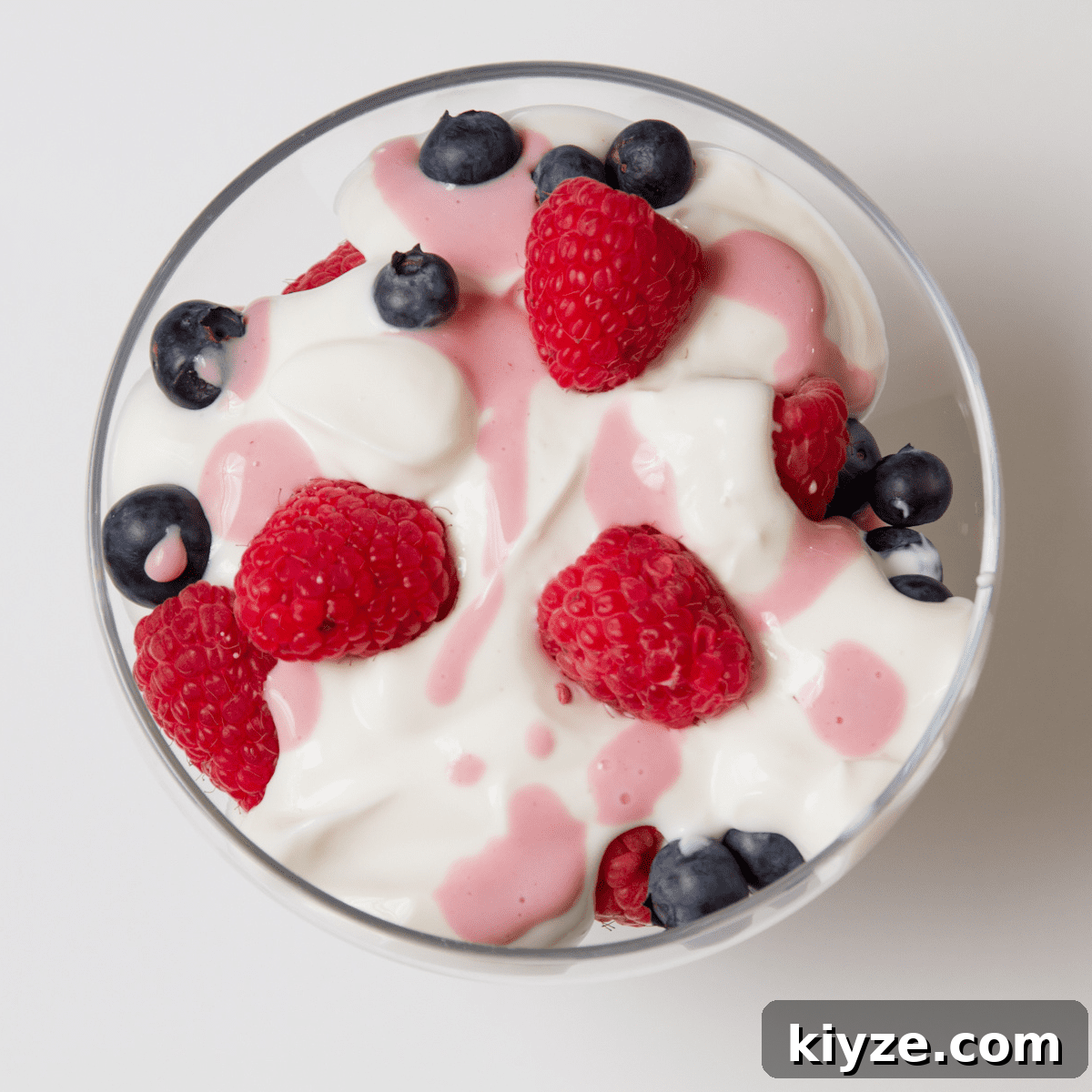 Prevent Toddler Grazing: Simple Strategies to Curb Constant Snacking 5 Clear bowl on white table, filled with white yogurt with blueberries, raspberries and pink fruit juice drizzled on top
