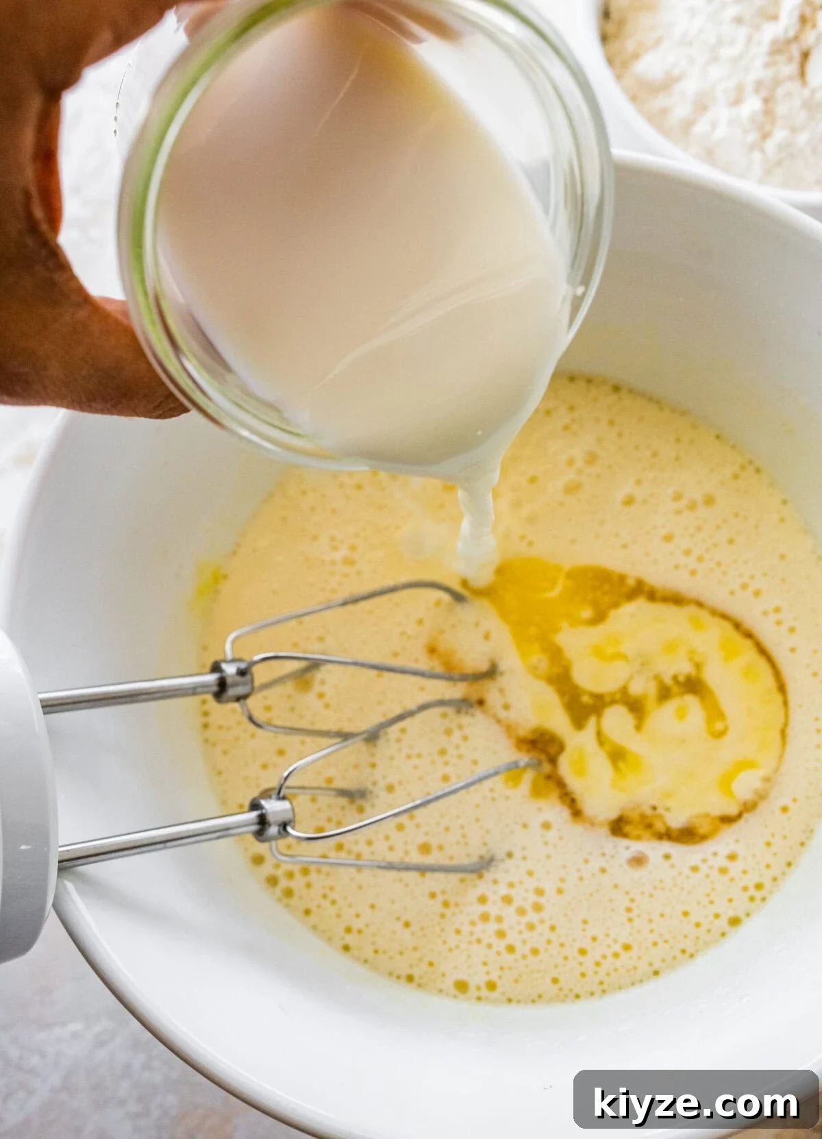 Italian Cannoli Cake Recipe: Classic Sicilian Dessert Guide 8 A person pouring milk into a bowl with eggs and flour.