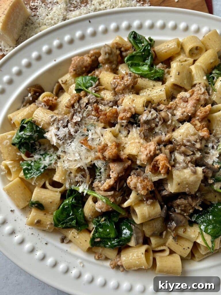 Creamy Pasta Norcina with Italian Sausage and Truffle Oil 2 Norcina Pasta on white platter with grated parmesan in background.