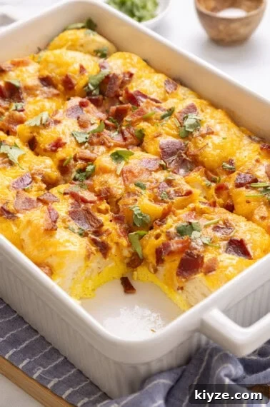 Bacon, egg and cheese biscuit casserole in casserole dish with one slice removed.