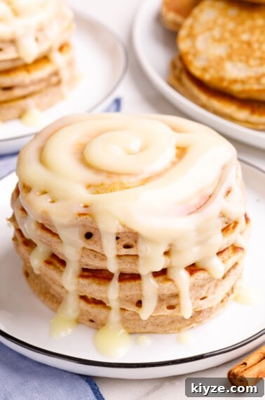 Crispy Cinnamon Churro Waffles Recipe 14 A stack of cinnamon pancakes topped with cream cheese glaze.