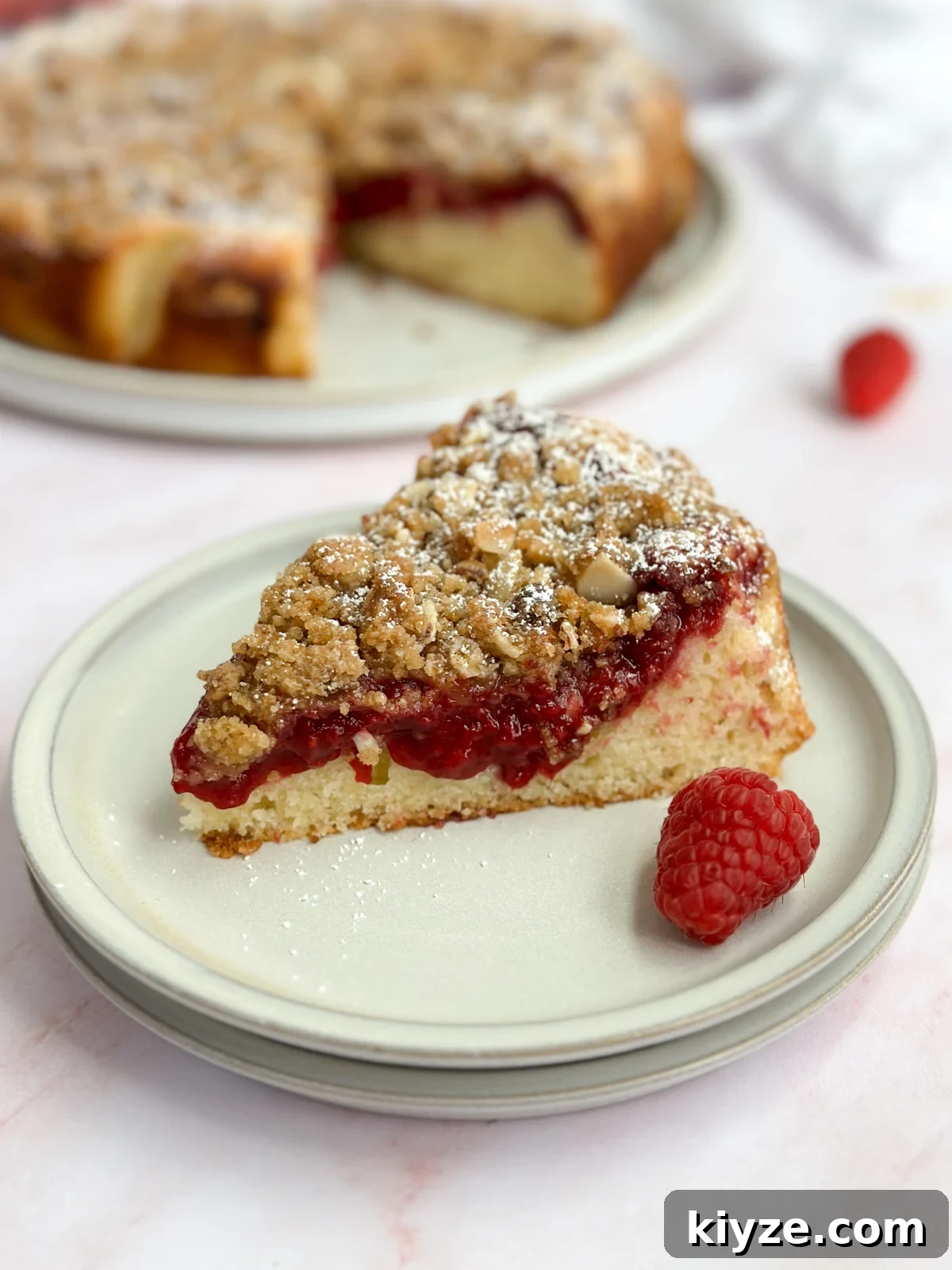 Almond Raspberry Layer Cake with Fresh Raspberry Glaze 2 a single slice of almond raspberry cake on a plate.