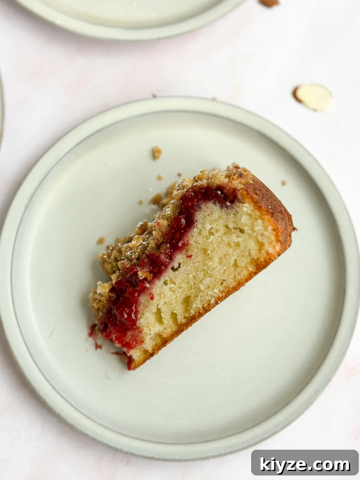 Almond Raspberry Layer Cake with Fresh Raspberry Glaze 13 a single slice of almond raspberry cake on its side to see the layers.