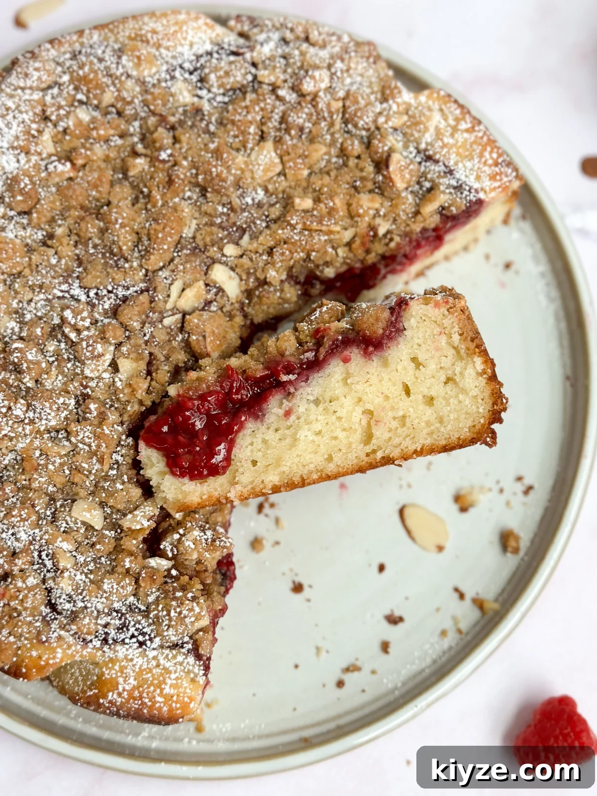 Almond Raspberry Layer Cake with Fresh Raspberry Glaze 14 a slice of cake sitting to the side of the rest of the cake.