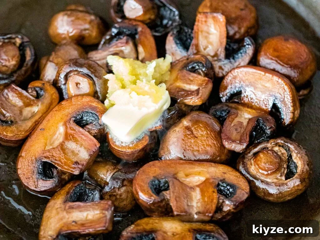 Garlic Butter Sautéed Mushrooms Recipe — Quick Flavorful Side 12 pan seared baby portobello mushrooms with minced garlic and a pad of butter added on top
