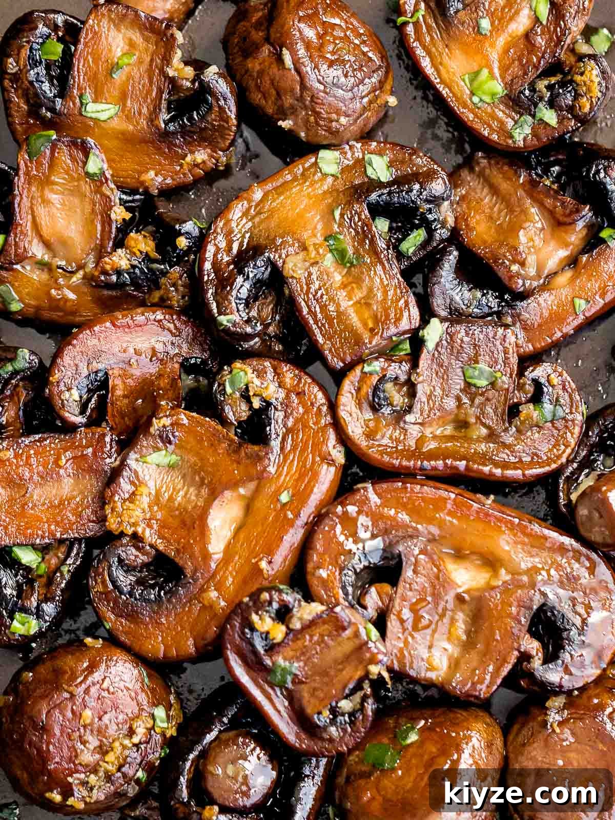 Garlic Butter Sautéed Mushrooms Recipe — Quick Flavorful Side 3 sauteed mushrooms laying flat on a pan and garnished with chopped parsley