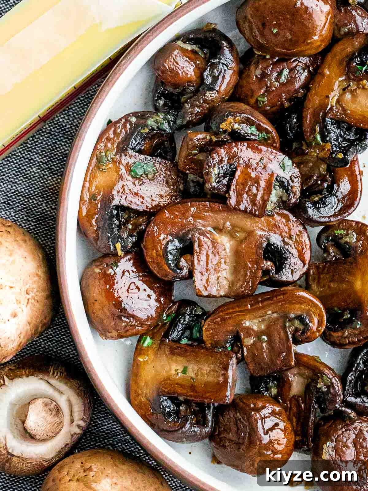 Garlic Butter Sautéed Mushrooms Recipe — Quick Flavorful Side 8 close up of sauteed mushrooms next to butter and uncooked mushrooms