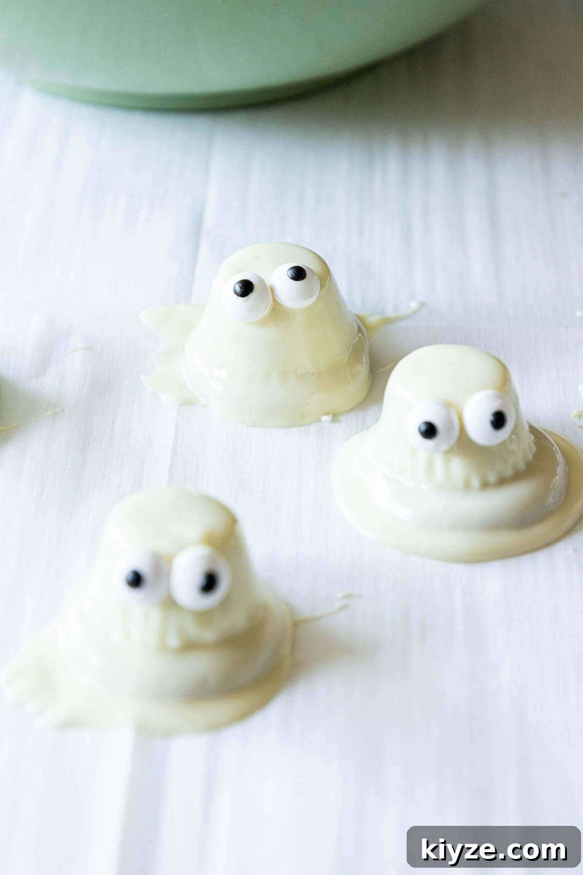 White Chocolate-Dipped Ghost Cookies: Spooky Halloween Treats 11 dipped ghost cookies setting on parchment paper
