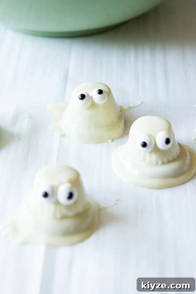 White Chocolate-Dipped Ghost Cookies: Spooky Halloween Treats 8 dipped ghosts setting on parchment paper
