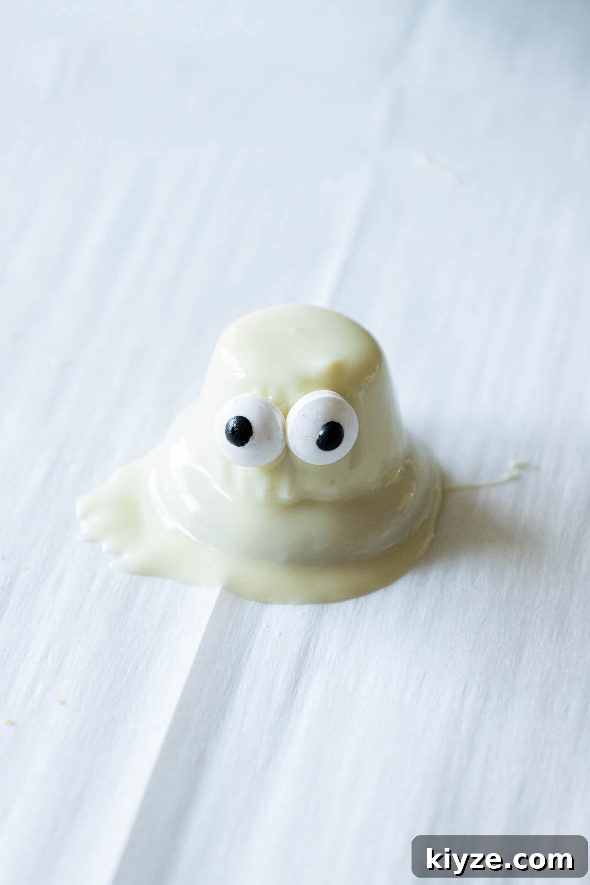 White Chocolate-Dipped Ghost Cookies: Spooky Halloween Treats 10 dipped cookie on baking sheet with candy eyes