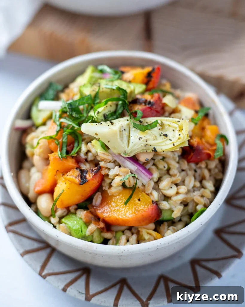 18 Flavorful Vegan Bean Salad Recipes for Every Occasion 13 summer farro and peach salad in a white bowl with fresh herbs and artichokes.