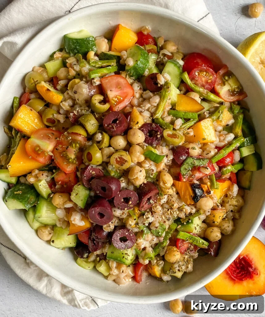 18 Flavorful Vegan Bean Salad Recipes for Every Occasion 20 mediterranean farro salad in a white serving dish next to peaches, lemon juice, and chickpeas.