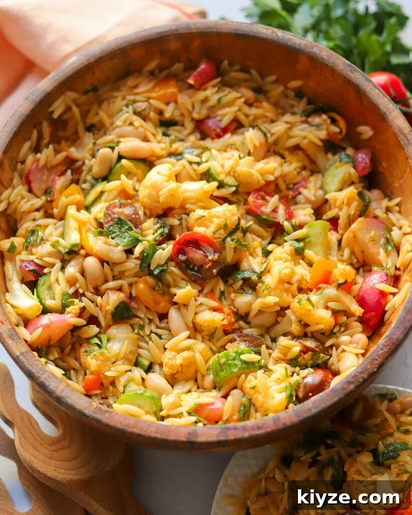 18 Flavorful Vegan Bean Salad Recipes for Every Occasion 4 white bean and orzo salad in a wooden bowl with lots of fresh veggies.