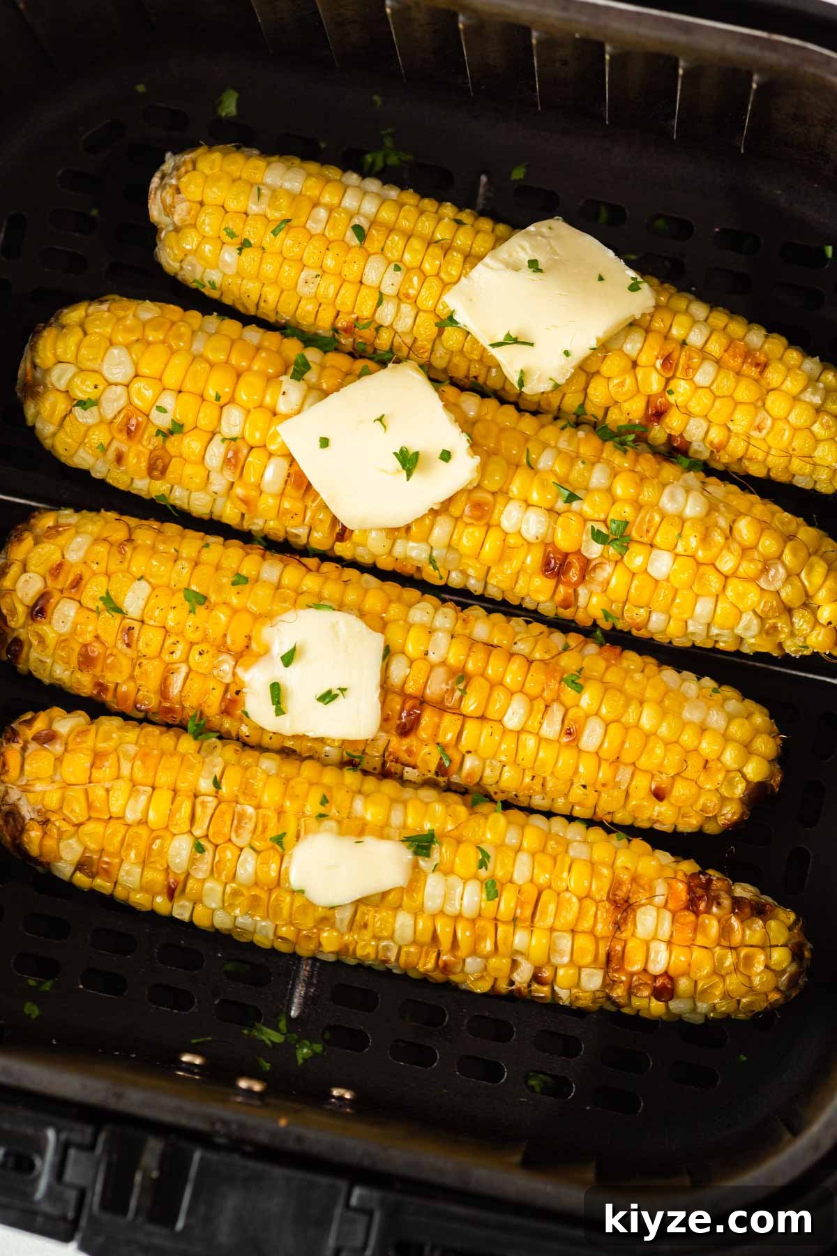 Crispy Air Fryer Corn on the Cob in 15 Minutes 2 corn on the cob with butter in the air fryer.