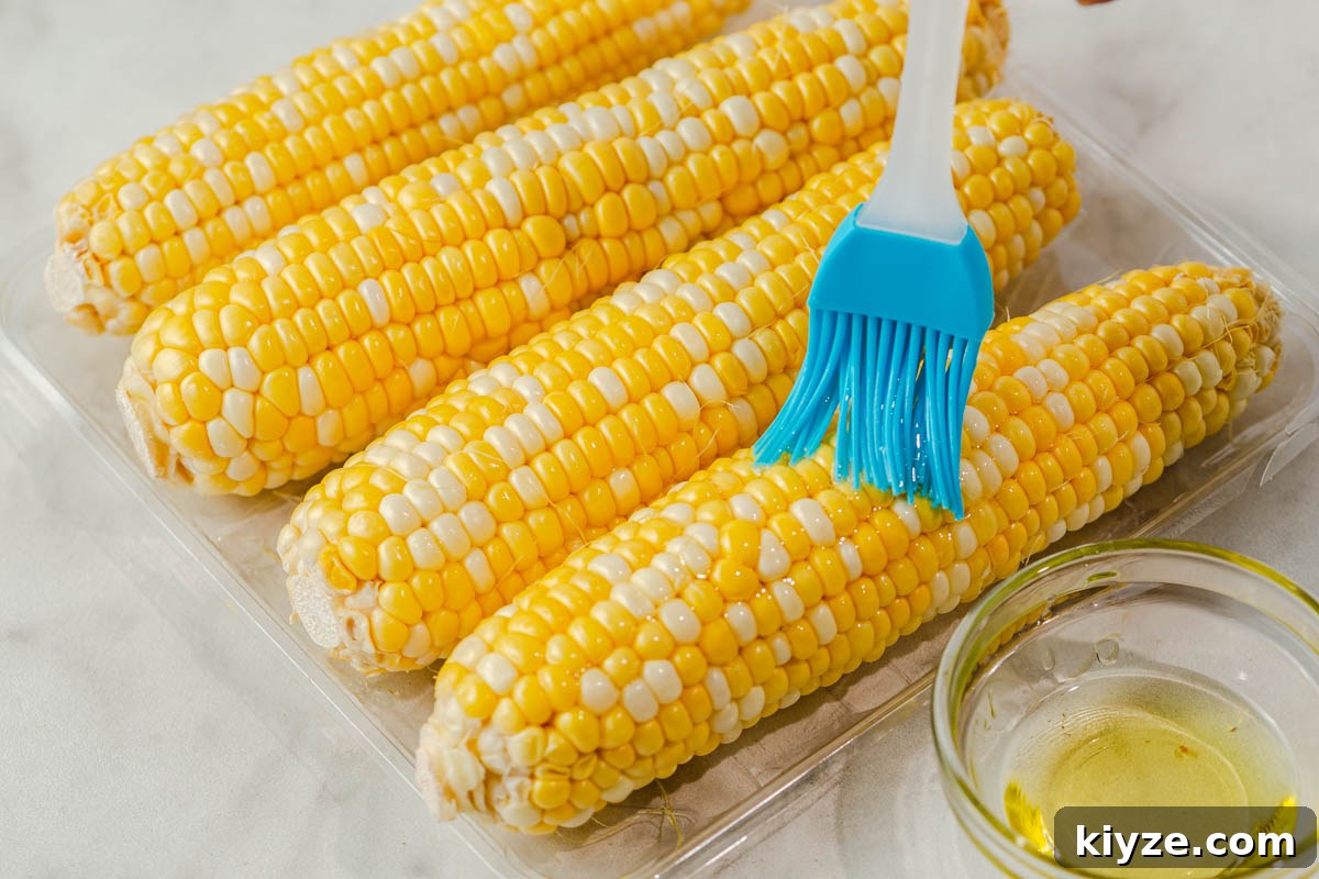 Crispy Air Fryer Corn on the Cob in 15 Minutes 4 brushing oil on the corn cobs.