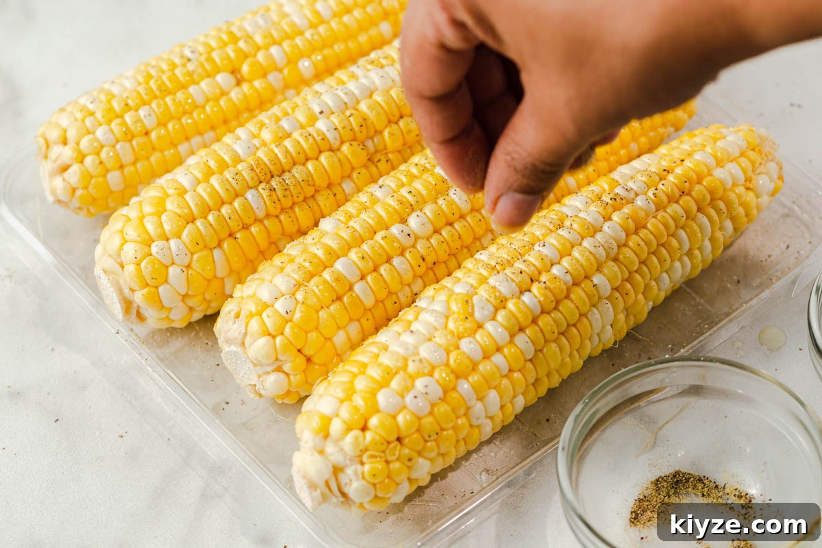 Crispy Air Fryer Corn on the Cob in 15 Minutes 5 adding salt and pepper to corn on the cob.
