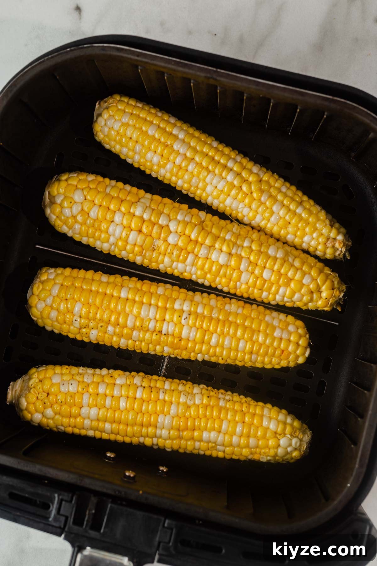 Crispy Air Fryer Corn on the Cob in 15 Minutes 6 placing the corn on the cob in the air fryer.