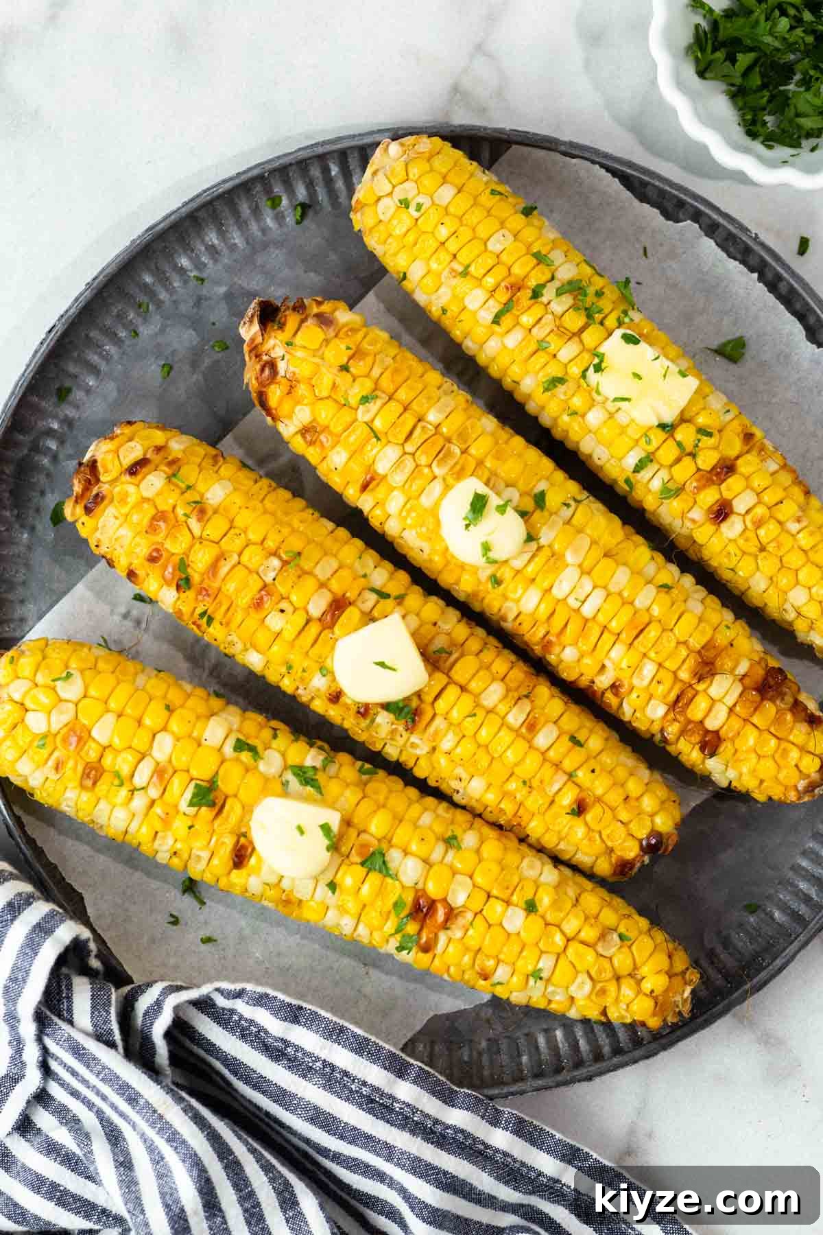 Crispy Air Fryer Corn on the Cob in 15 Minutes 9 air fryer corn on the cob with butter on a plate.