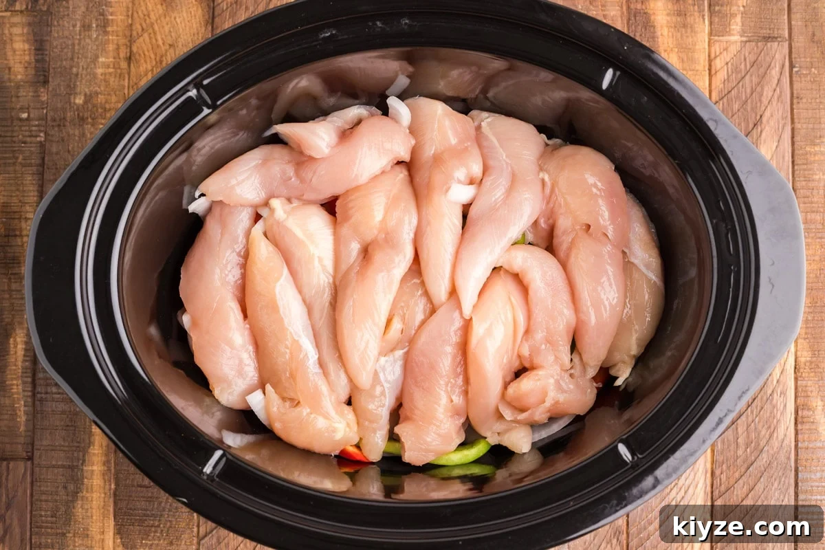 Slow Cooker Chicken Fajitas Recipe for Juicy, Flavorful Meals 4 chicken tenders on top of onions and bell peppers