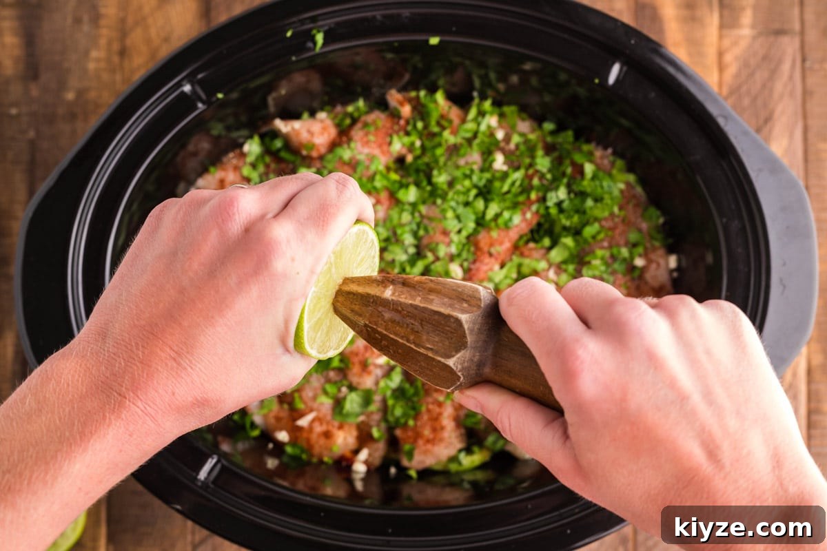 Slow Cooker Chicken Fajitas Recipe for Juicy, Flavorful Meals 5 lime juice being squeezed over chicken, peppers, onions and cilantro in slow cooker.