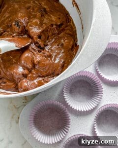 Blackberry Chocolate Cupcakes Recipe with Rich Ganache Filling 8 process of mixing Blackberry Chocolate Cupcakes batter in white bowl with muffin tin in the background