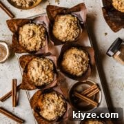 Cinnamon Streusel Muffins Recipe with Crunchy Brown Sugar Topping 18 Streusel topped muffins in brown paper parchment liners in a muffin tin.