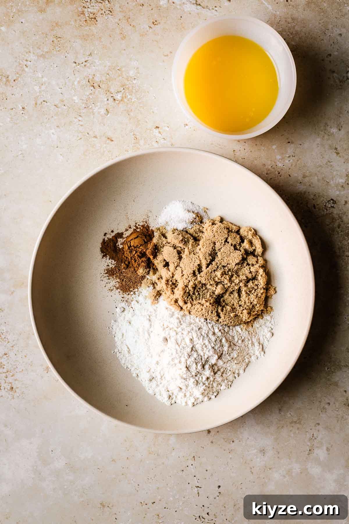 Cinnamon Streusel Muffins Recipe with Crunchy Brown Sugar Topping 4 A shallow tan bowl filled with dry ingredients and a small bowl of melted butter.