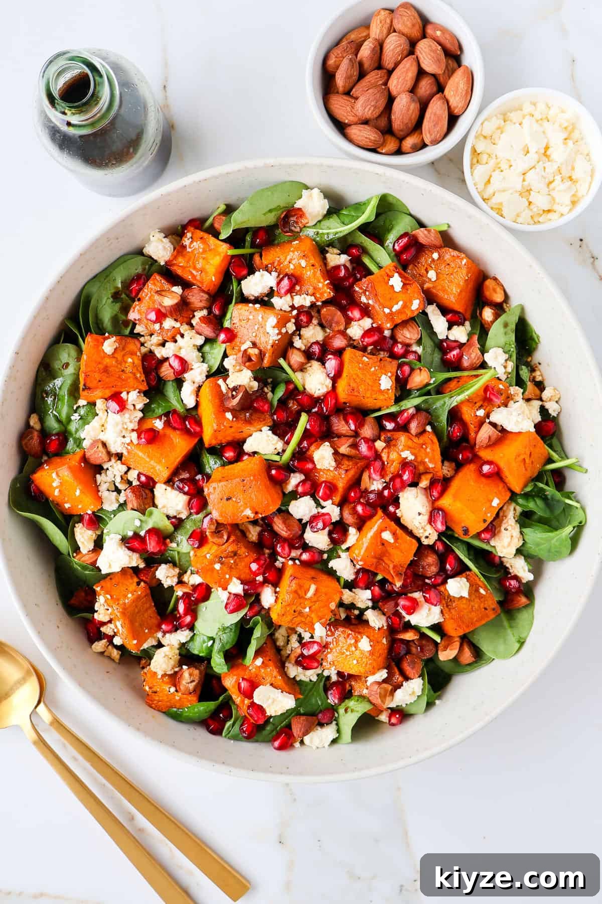 Roasted Pumpkin, Spinach and Feta Salad with Maple Vinaigrette 8 Pumpkin salad in a bowl. Gold cutlery, dressing, almonds and feta on the side.