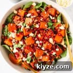 Pumpkin salad in a bowl with gold cutlery.