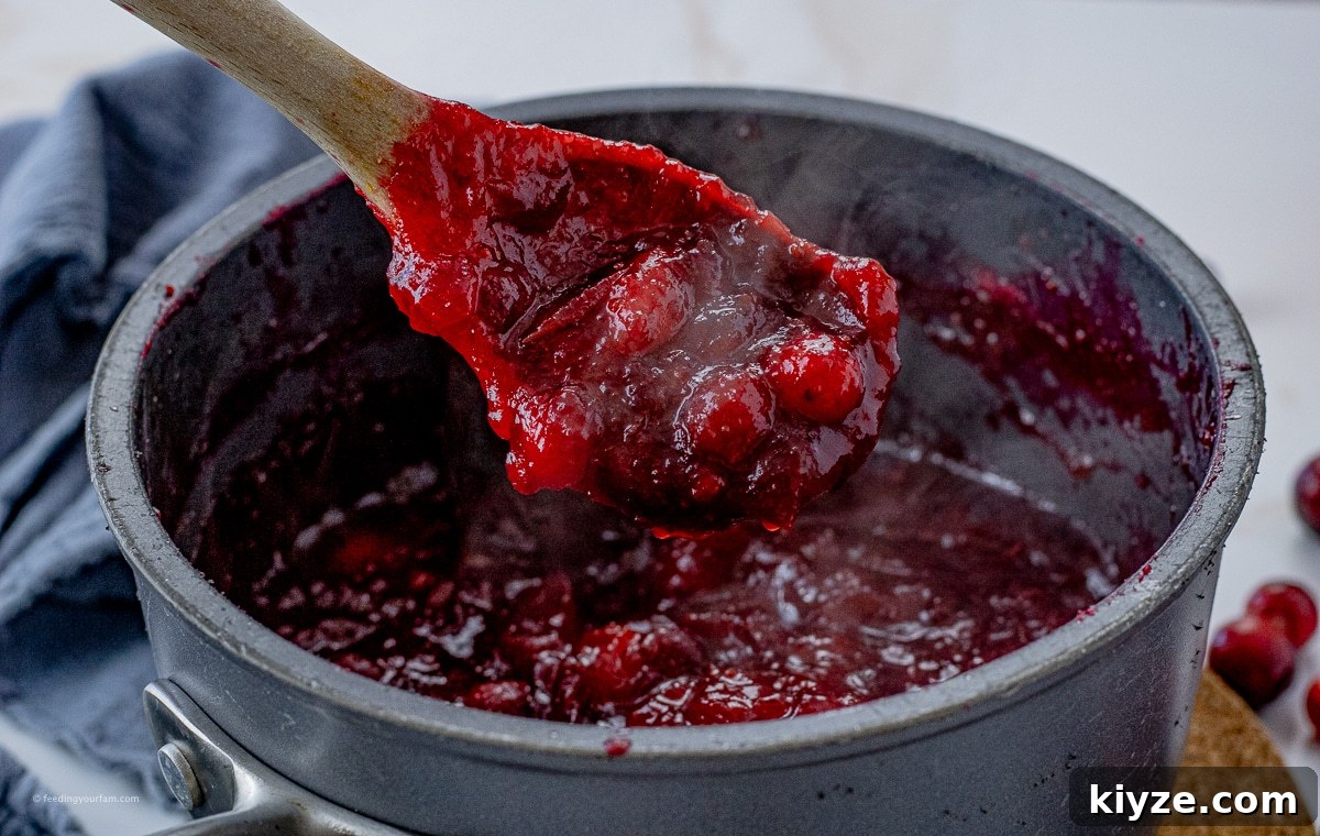 Tangy Cranberry Orange Sauce Recipe for Holiday Feasts 4 wooden spoon scooping out steaming, homemade cranberry sauce