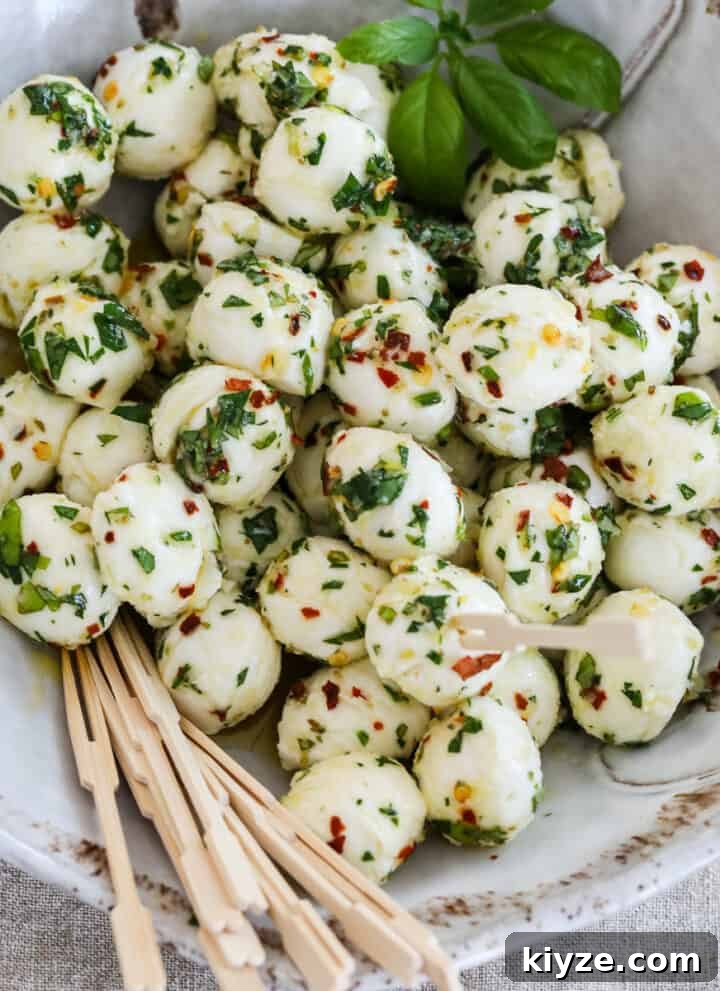 Marinated mozzarella balls in a beige ceramic dish with appetizer toothpicks.