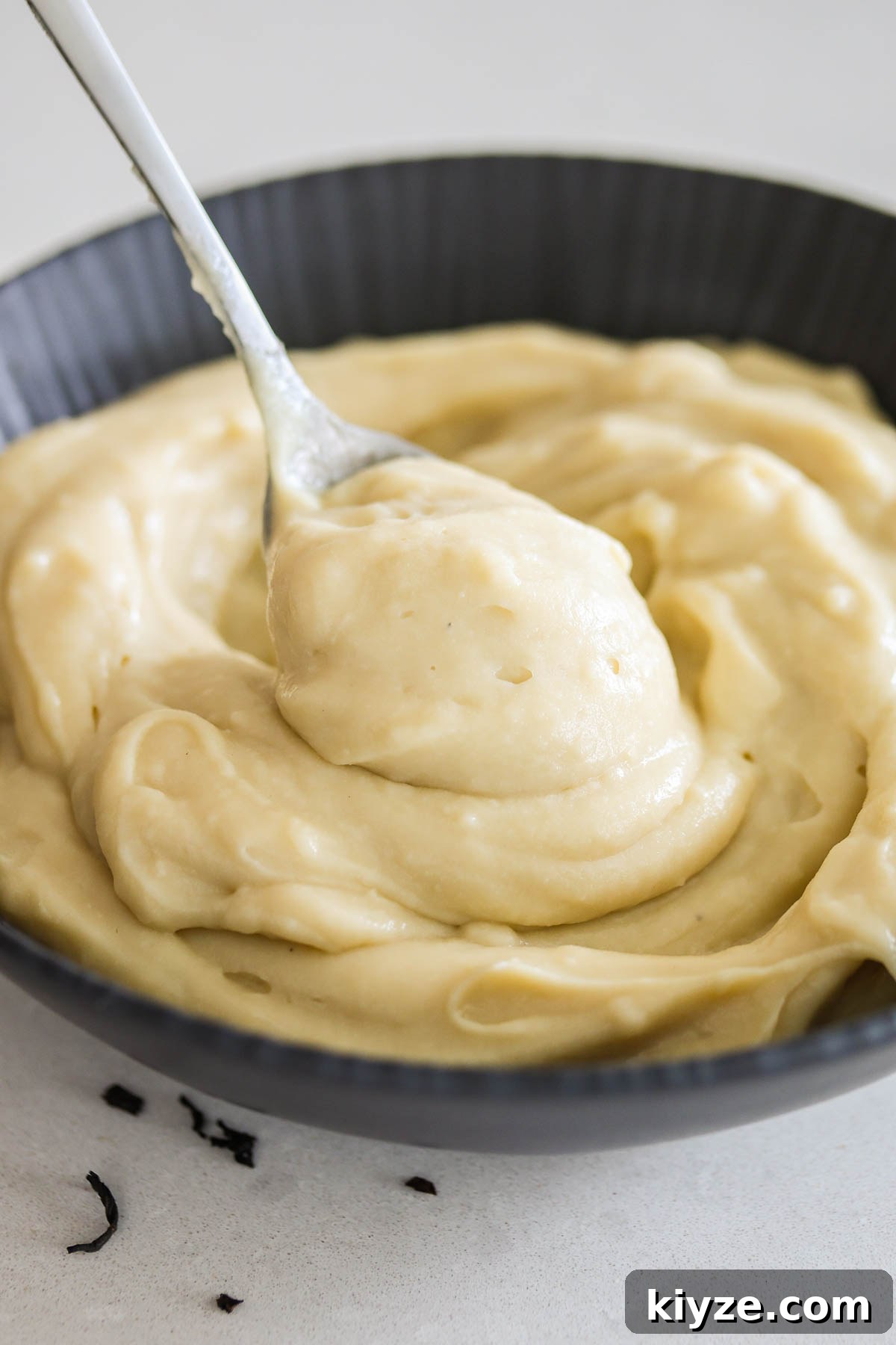 Earl Grey Custard Recipe: Silky Tea-Infused Pastry Cream 11 Earl Grey custard in a black bowl with spoon.
