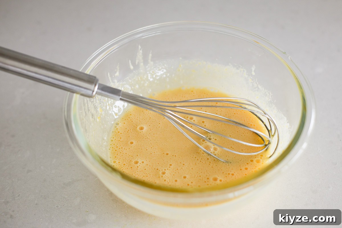 Earl Grey Custard Recipe: Silky Tea-Infused Pastry Cream 8 Mixture in a glass bowl with whisk.