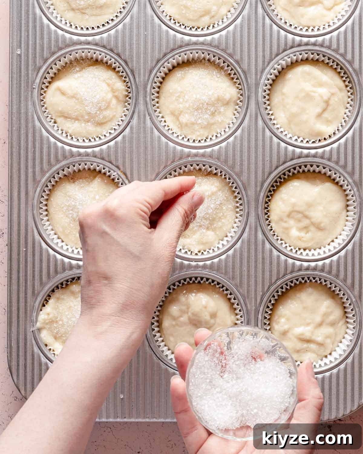 Fluffy Buttermilk Muffins Recipe for Tender Homemade Muffins 11 hand sprinkling coarse sugar over muffin batter in cupcake tin.