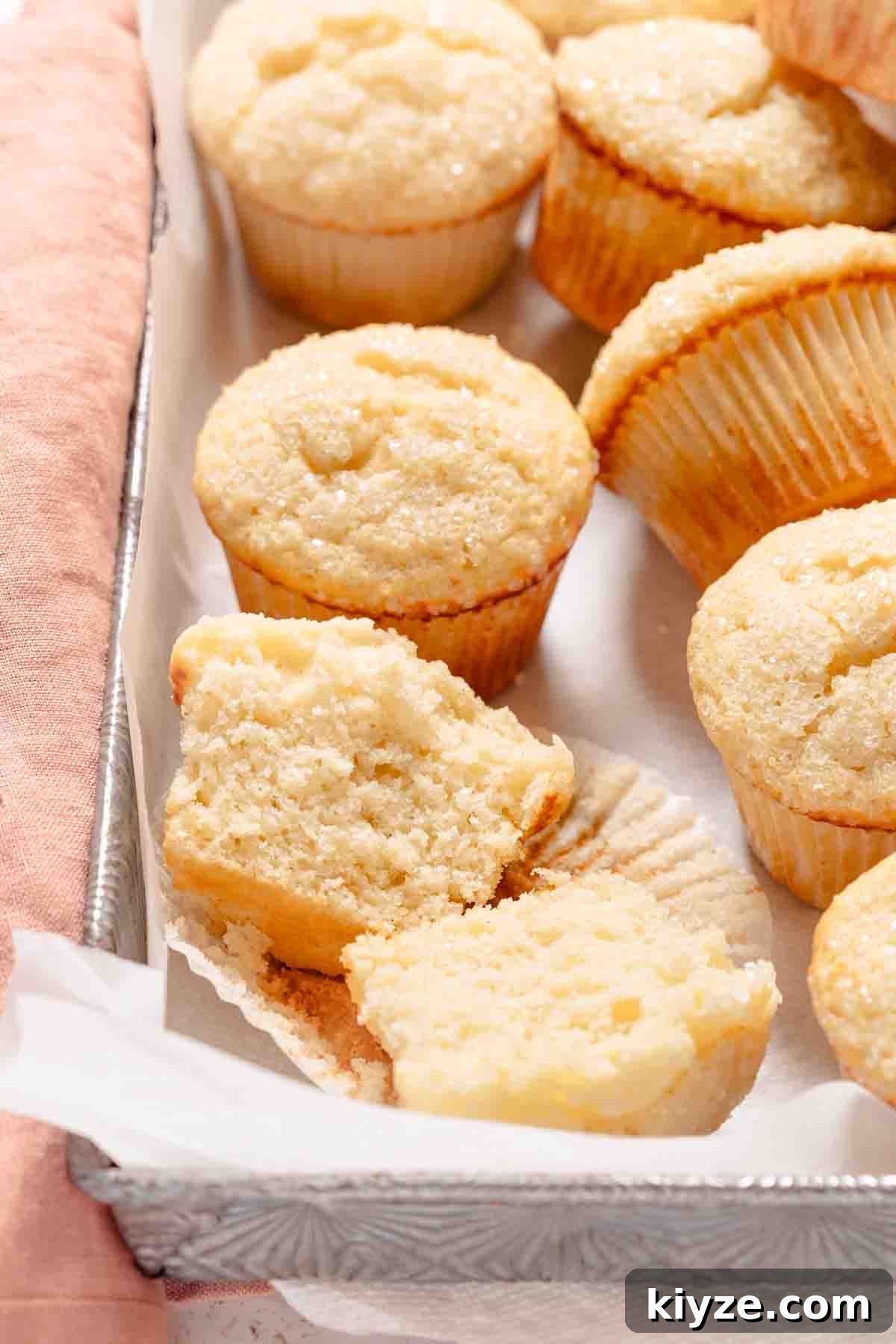 Fluffy Buttermilk Muffins Recipe for Tender Homemade Muffins 13 split buttermilk muffin in muffin liner with other muffins in the background.