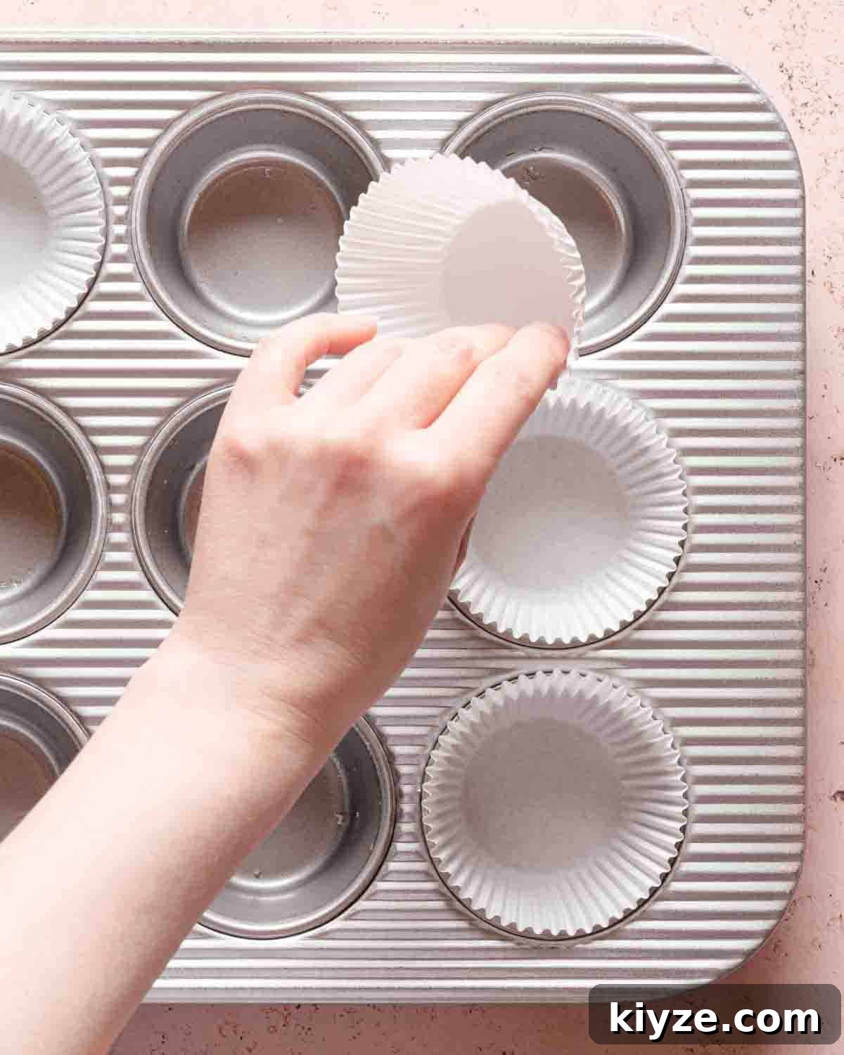 Fluffy Buttermilk Muffins Recipe for Tender Homemade Muffins 4 hand placing paper muffin liners in cupcake tin.