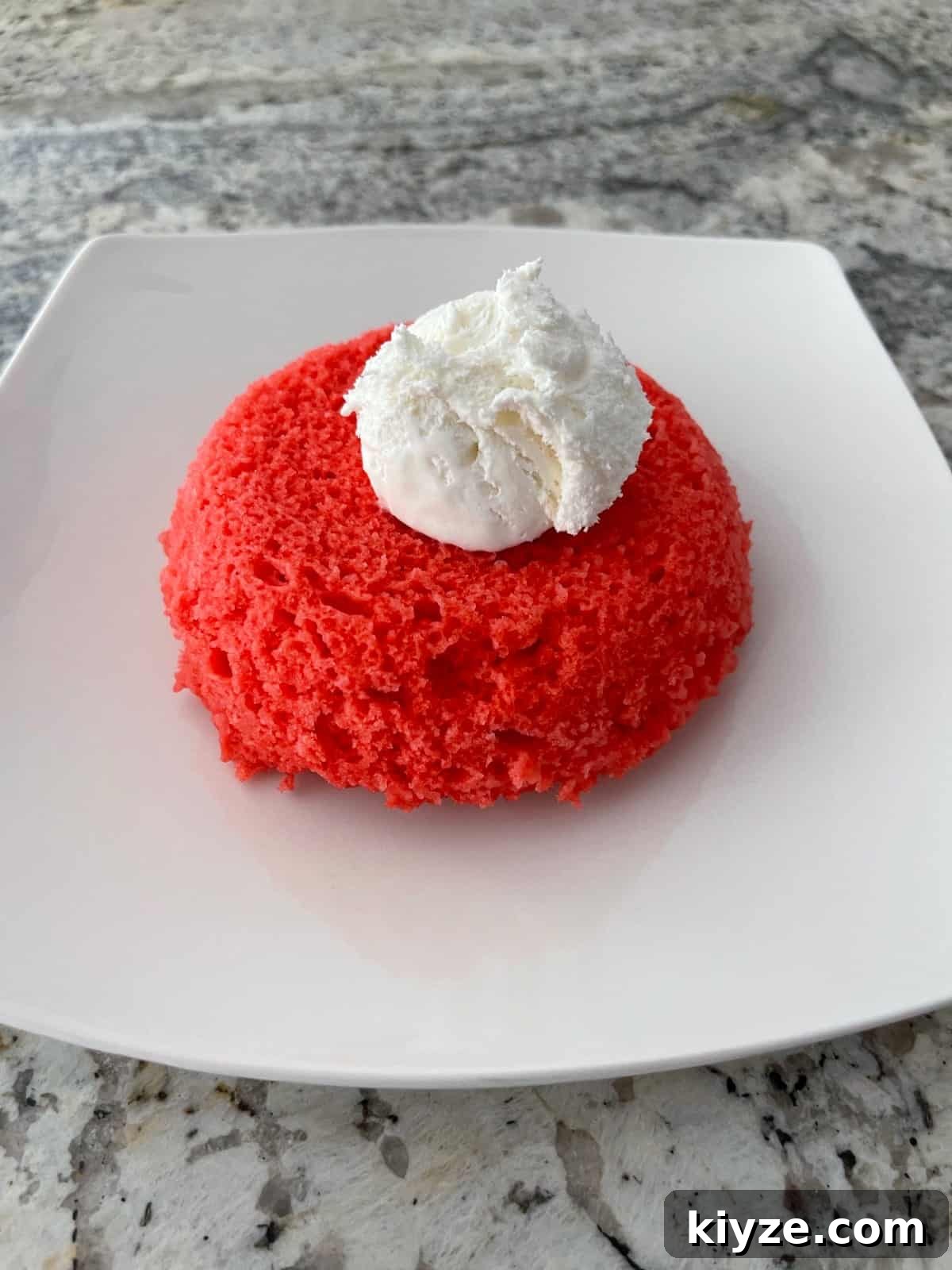 Microwave Mug Jello Cake Recipe: Quick Single-Serve Dessert 8 Raspberry Jell-o microwave cake topped with light whipped topping on small white plate.