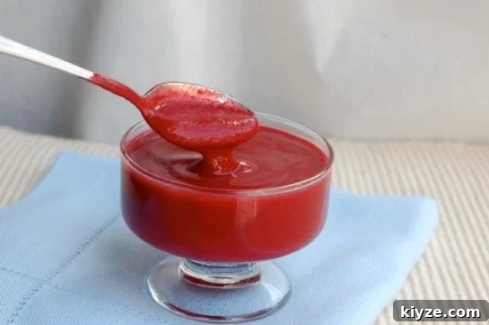 Microwave Mug Jello Cake Recipe: Quick Single-Serve Dessert 10 Simple raspberry sauce in glass dish with spoon.