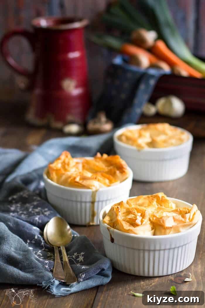 Crispy Fillo Vegetable Pot Pie with Savory Herb Filling 2 Individual pot pies with vegetables on a table with spoons.