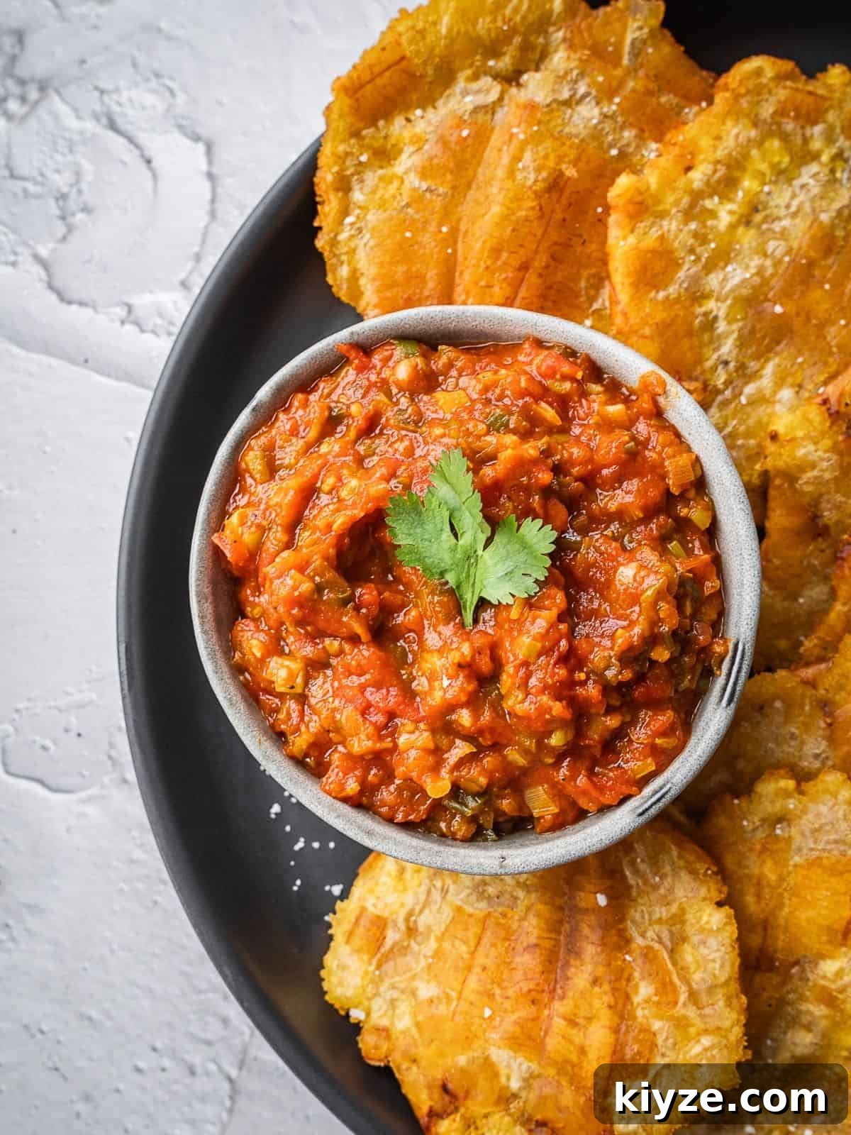 Hogao: Authentic Colombian Tomato and Scallion Creole Sauce Recipe 7 Colombian hogao sauce in a bowl surrounded by fried plantains.