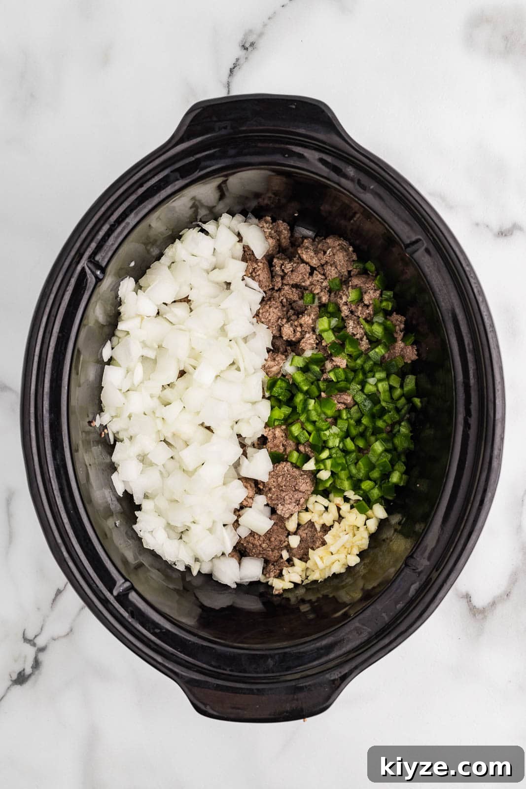 Slow Cooker No-Bean Chili Recipe for Tender, Flavorful Meat 5 overhead view of black slow cooker with ground beef and turkey, onion, garlic, and jalapeno