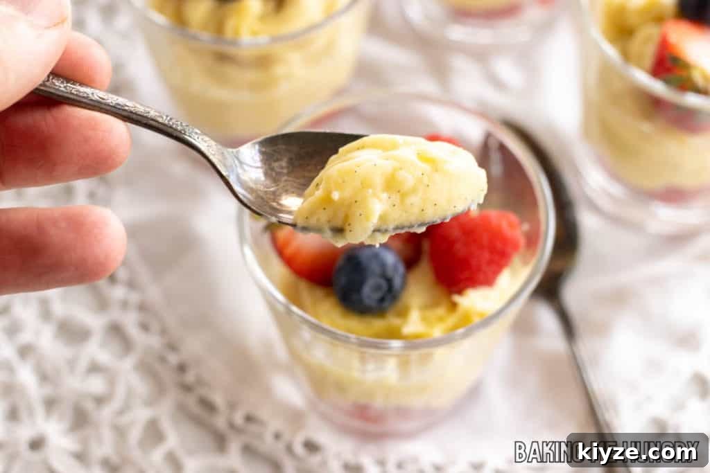 Silky Vanilla Bean Custard Recipe 12 hand holding up spoon with bite of vanilla bean custard