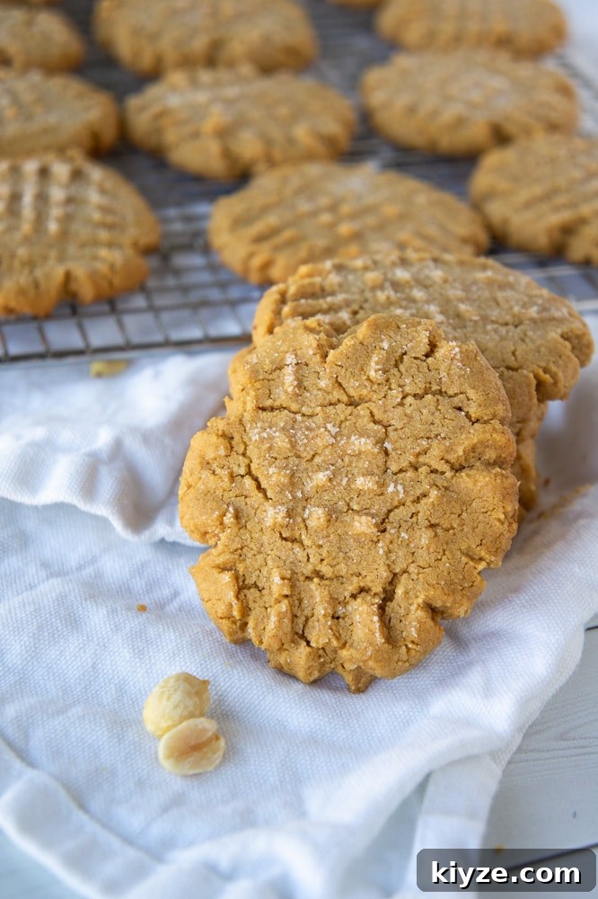 a stack of flourless peanut butter cookies in front of a cooling rack of cookies