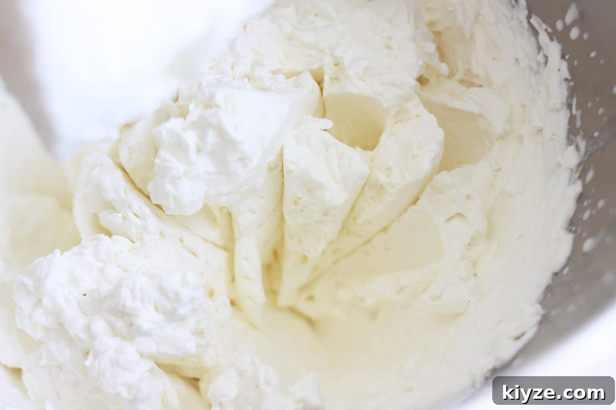 the bowl of a kitchen aid mixer full of whipped cream