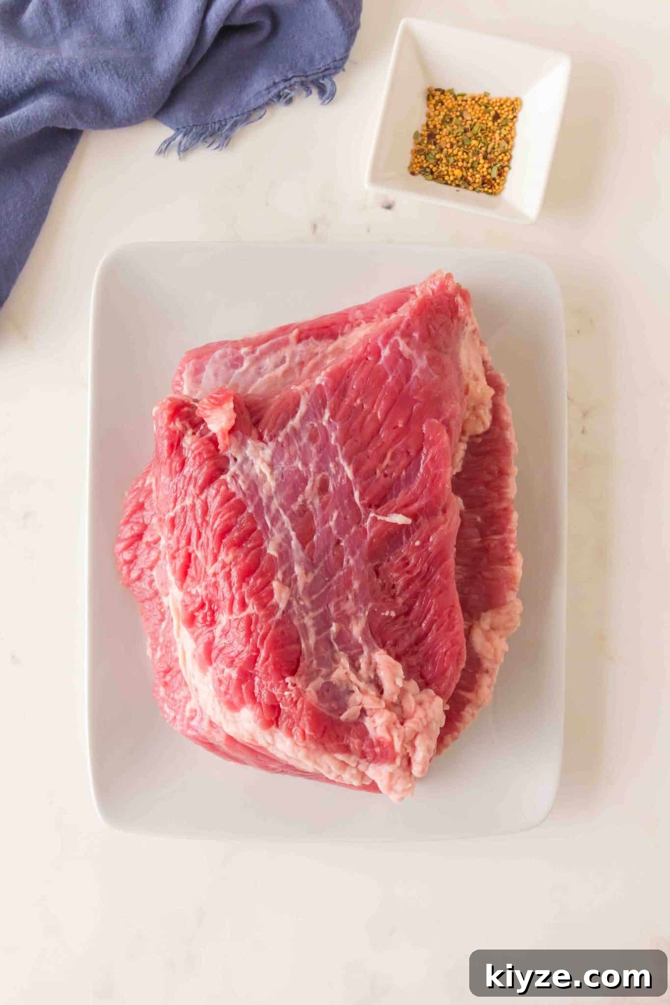 Juicy Oven-Baked Corned Beef Brisket Recipe 3 Top down view of the ingredients used to make oven-baked corned beef including the beef brisket and spices. Hostess At Heart